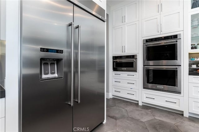 kitchen featuring white cabinets, stainless steel appliances, and dark tile patterned flooring