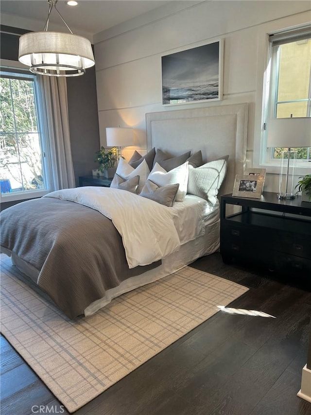 bedroom featuring a notable chandelier and dark wood-type flooring