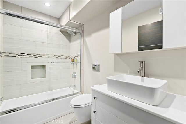 full bathroom featuring shower / bath combination with glass door, vanity, and toilet