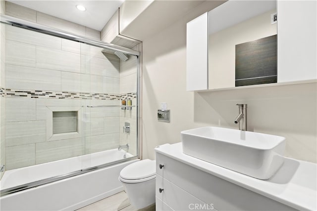 full bathroom featuring enclosed tub / shower combo, vanity, toilet, and tile patterned floors