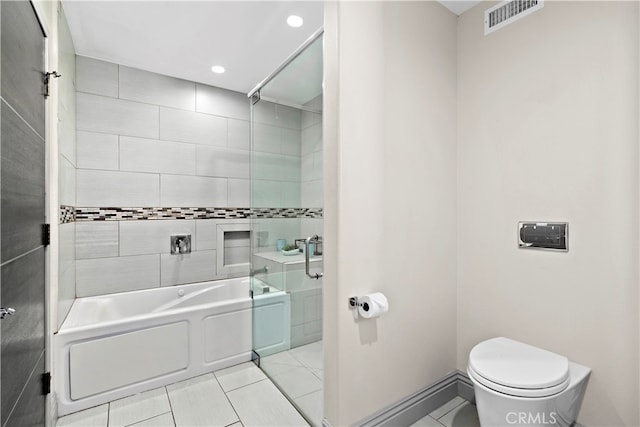 bathroom with tiled shower / bath combo, toilet, and tile patterned floors