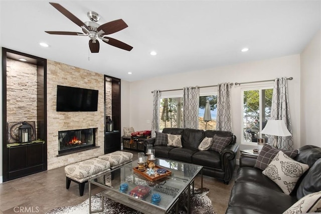 living room with a stone fireplace and ceiling fan