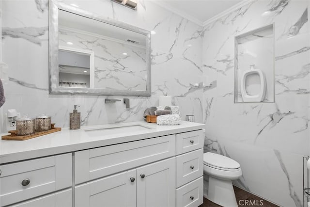 bathroom featuring toilet, vanity, tile walls, and ornamental molding