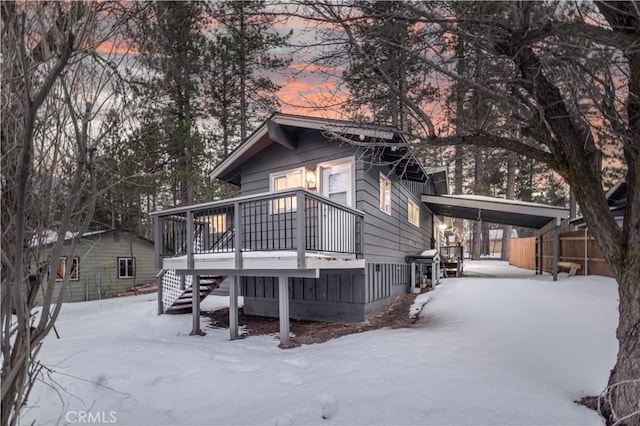 snow covered back of property with a deck