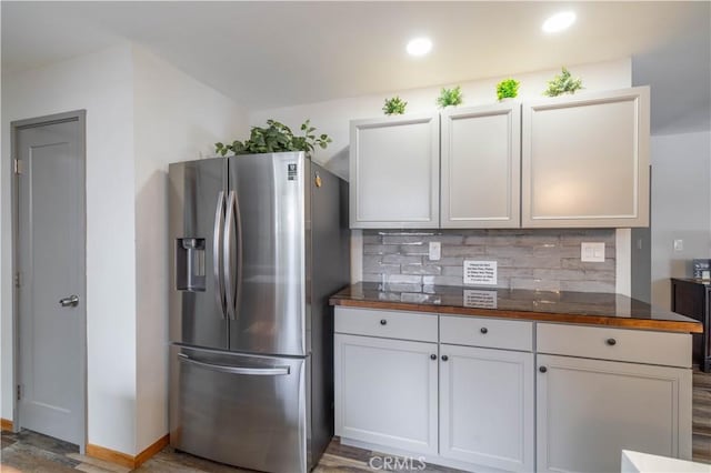 kitchen featuring hardwood / wood-style floors, backsplash, white cabinets, stainless steel refrigerator with ice dispenser, and butcher block countertops