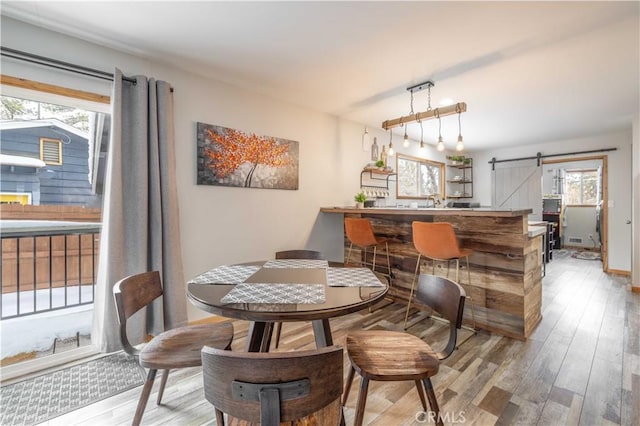 dining area featuring a barn door, light hardwood / wood-style flooring, and plenty of natural light