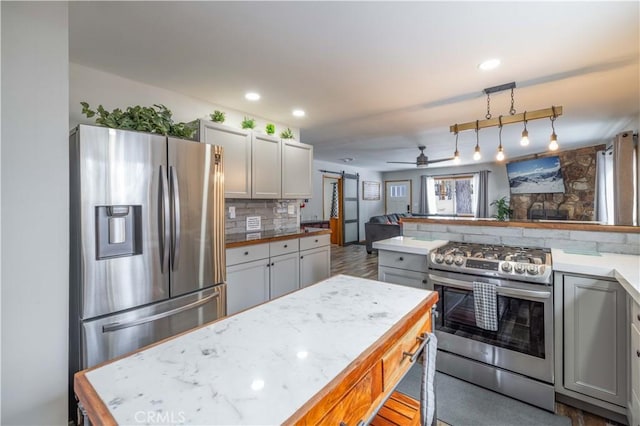 kitchen featuring decorative backsplash, stainless steel appliances, ceiling fan, gray cabinets, and hanging light fixtures