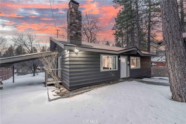 snow covered house featuring a carport