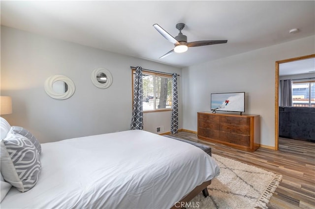 bedroom with hardwood / wood-style flooring, ceiling fan, and multiple windows