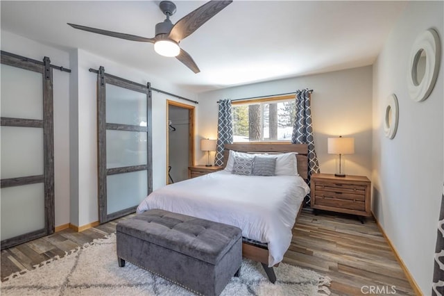 bedroom with hardwood / wood-style floors, a barn door, and ceiling fan