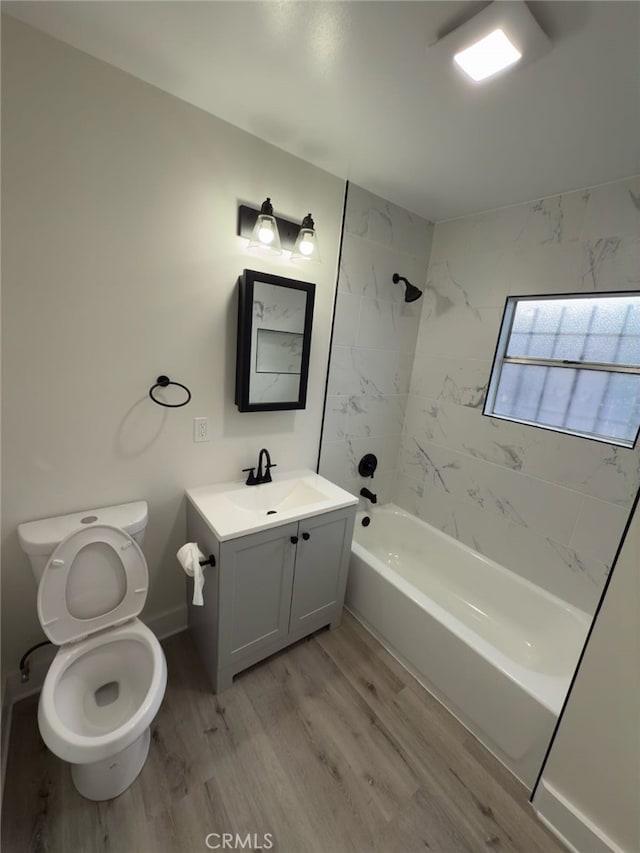 full bathroom with toilet, vanity,  shower combination, wood finished floors, and baseboards