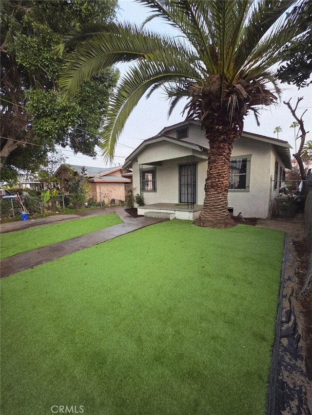back of house featuring stucco siding and a yard