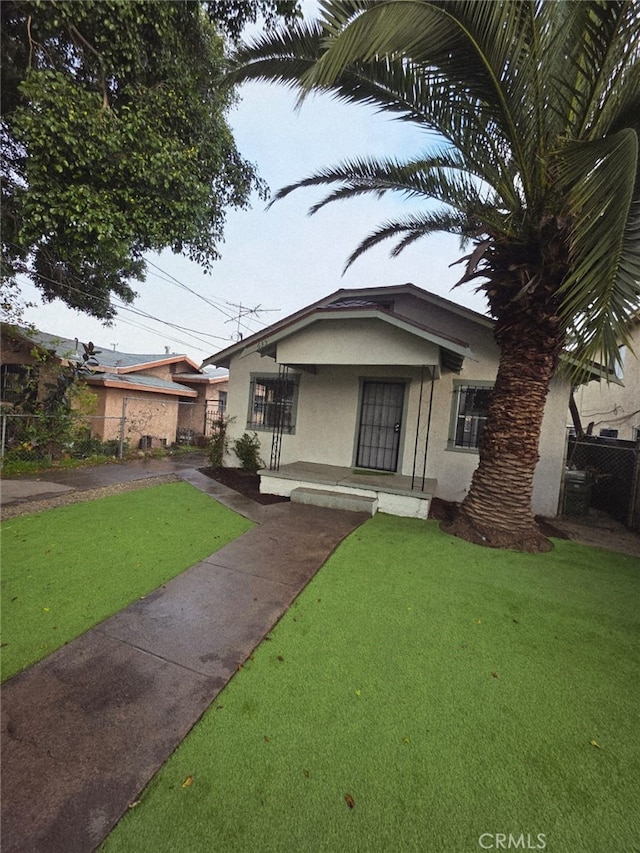 view of front of home with a front yard, stucco siding, and fence