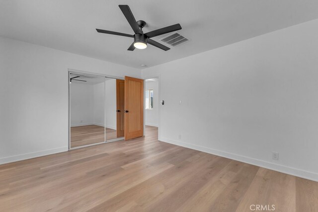 unfurnished bedroom with a closet, light wood-type flooring, and ceiling fan