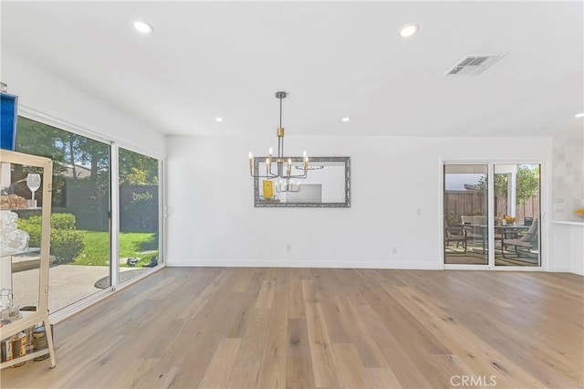 unfurnished dining area featuring a chandelier, light hardwood / wood-style flooring, and plenty of natural light