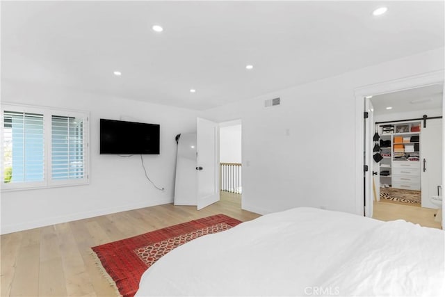 bedroom with a spacious closet and light hardwood / wood-style flooring