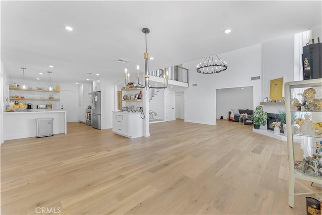 unfurnished living room with a towering ceiling and light wood-type flooring