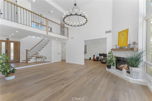 living room featuring a high ceiling, light hardwood / wood-style flooring, and a notable chandelier