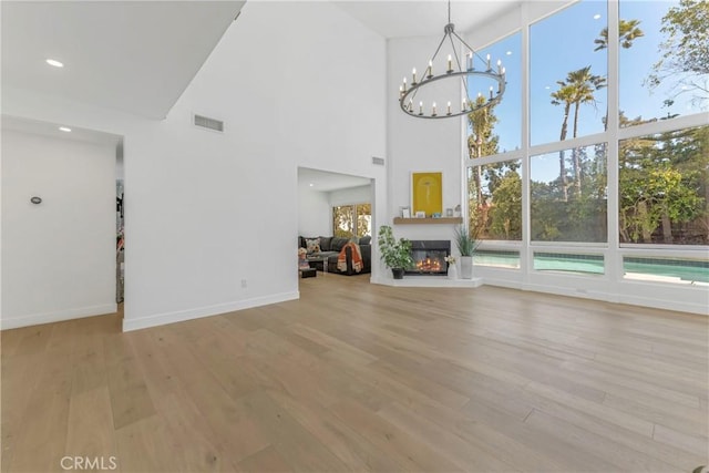 unfurnished living room with a high ceiling and light wood-type flooring