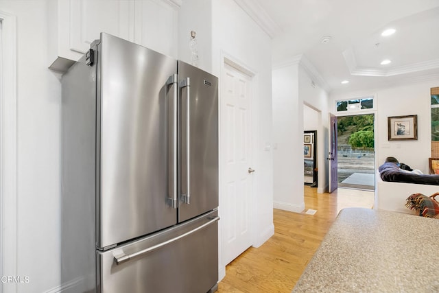 kitchen featuring high end refrigerator, ornamental molding, light wood-type flooring, and white cabinetry