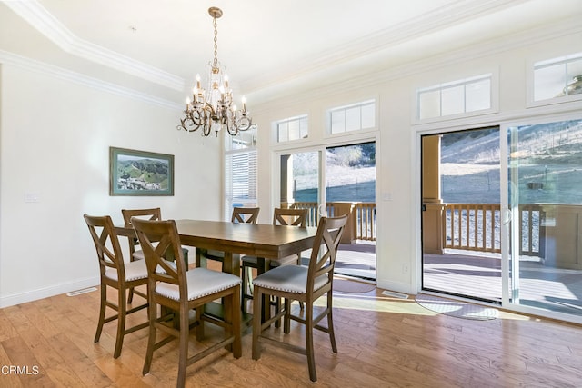 dining area featuring light wood-type flooring, crown molding, and a notable chandelier