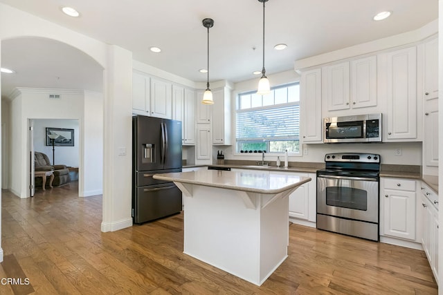 kitchen featuring light hardwood / wood-style flooring, white cabinetry, stainless steel appliances, a center island, and crown molding