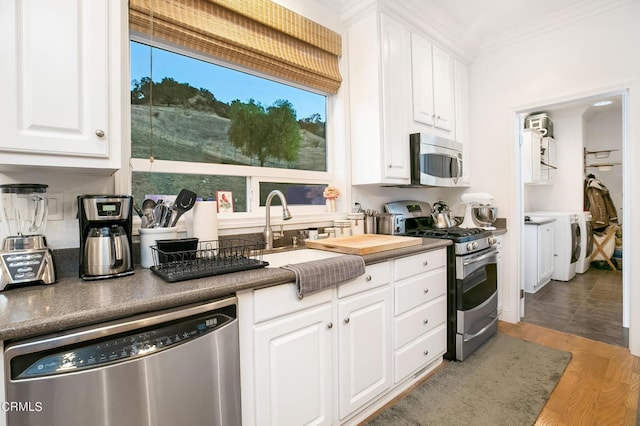 kitchen with light wood-type flooring, washer / clothes dryer, white cabinets, stainless steel appliances, and crown molding