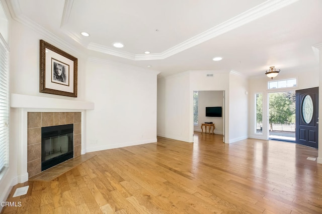 unfurnished living room with light wood-type flooring, a tile fireplace, and crown molding