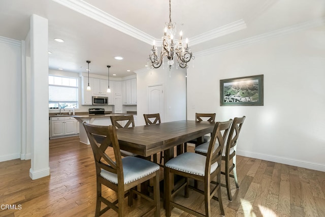 dining room featuring an inviting chandelier, ornamental molding, hardwood / wood-style floors, and sink