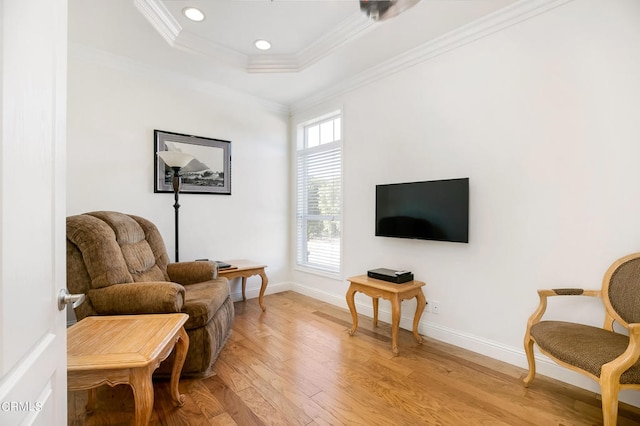 sitting room featuring light wood-type flooring, a raised ceiling, and crown molding