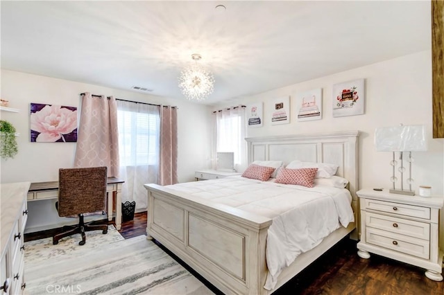 bedroom with a chandelier and dark wood-type flooring