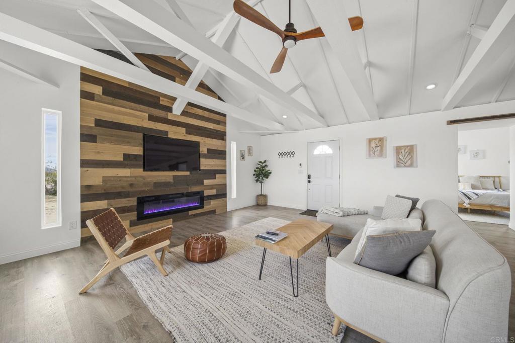 living room with ceiling fan, wood walls, beamed ceiling, hardwood / wood-style flooring, and high vaulted ceiling