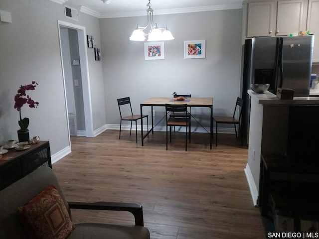 dining room featuring wood-type flooring, ornamental molding, and an inviting chandelier