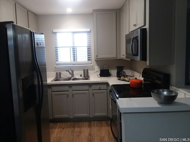 kitchen featuring sink, black appliances, gray cabinetry, and light wood-type flooring