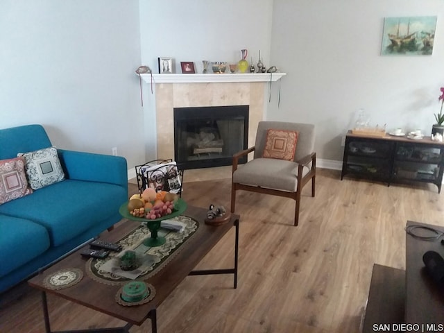 living room with a tiled fireplace and light wood-type flooring