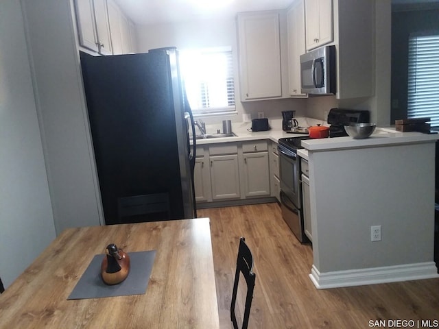 kitchen with light hardwood / wood-style floors, appliances with stainless steel finishes, wooden counters, and white cabinets