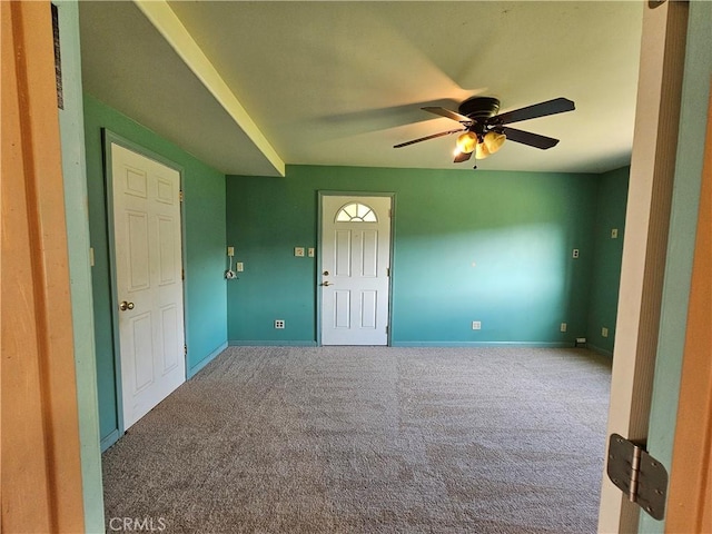 carpeted spare room featuring baseboards and a ceiling fan