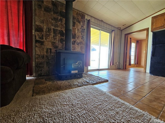 unfurnished living room with a wood stove, tile patterned flooring, and vaulted ceiling