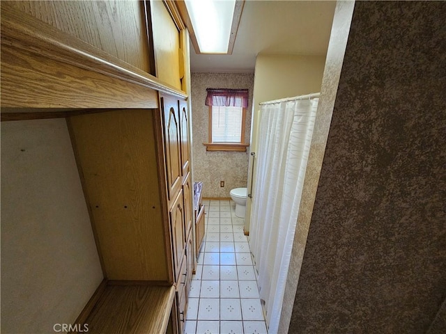 full bathroom with baseboards, wallpapered walls, toilet, and tile patterned floors