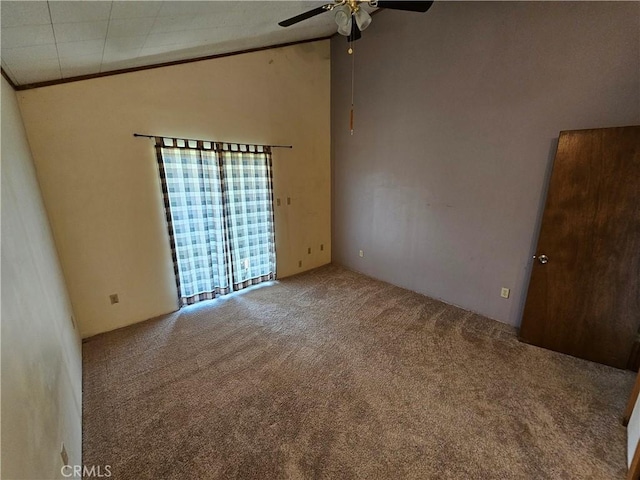 carpeted empty room with ornamental molding, high vaulted ceiling, and a ceiling fan