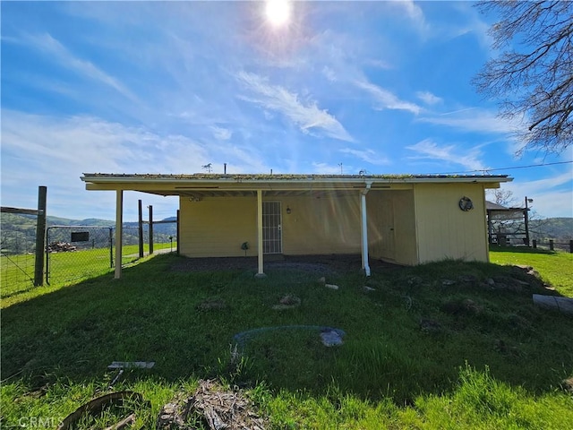 rear view of house with a lawn and fence