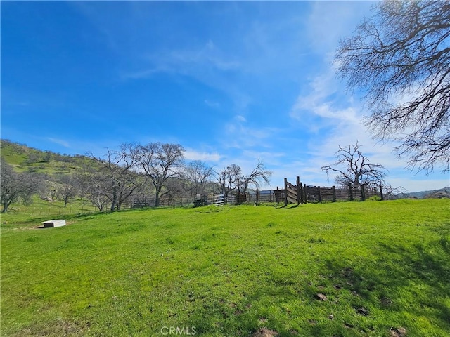 view of yard with fence and a rural view