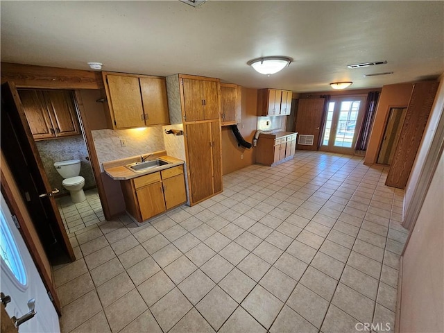 kitchen with brown cabinetry, light countertops, and a sink