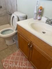 bathroom featuring a shower, tile patterned flooring, vanity, and toilet