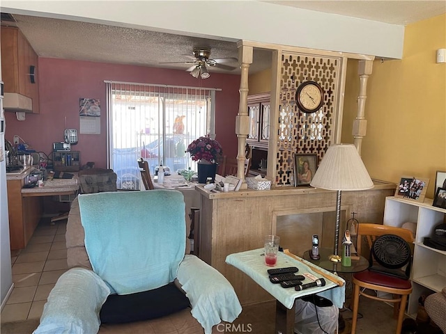 living room featuring ceiling fan, light tile patterned floors, and a textured ceiling