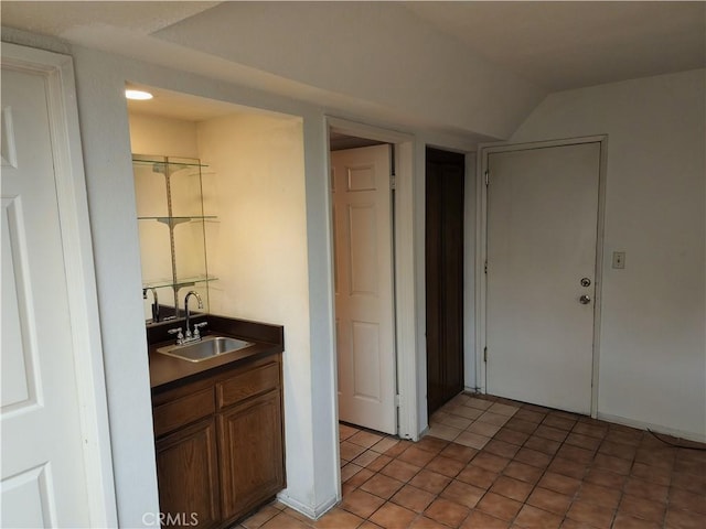 bar featuring light tile patterned floors, vaulted ceiling, and sink