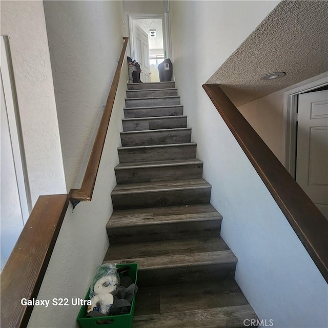 stairway featuring a textured ceiling and hardwood / wood-style flooring