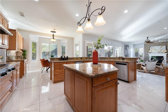 kitchen with ceiling fan, a fireplace, a center island, hanging light fixtures, and appliances with stainless steel finishes