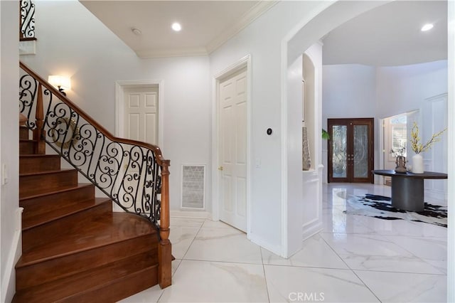 entryway with crown molding and french doors