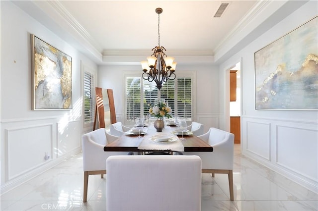 dining area with a tray ceiling, ornamental molding, and a chandelier